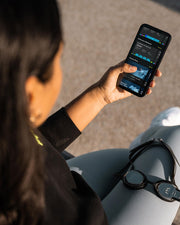 Woman sitting and looking at a swim tracker app with goggles on her knee